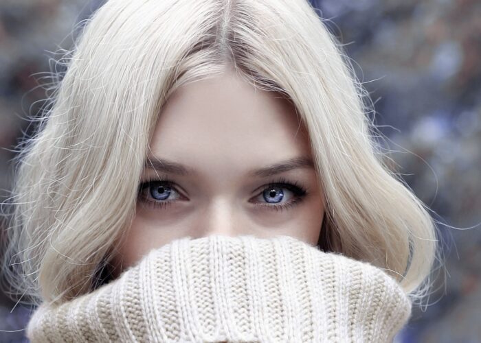 Blonde woman with blue eyes and face covered to the nose with fluffy jumper